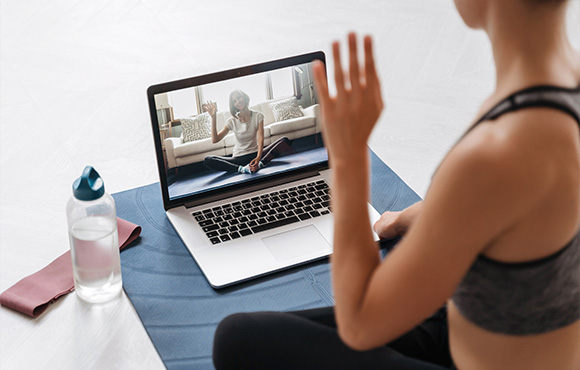 woman practicing yoga at home using laptop during online class with instructor and water bottle on mat 4 wellness tips