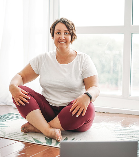 woman sitting cross-legged on a yoga mat in a bright room wearing comfortable clothing practicing mindfulness and relaxation techniques 4 ways to improve wellness