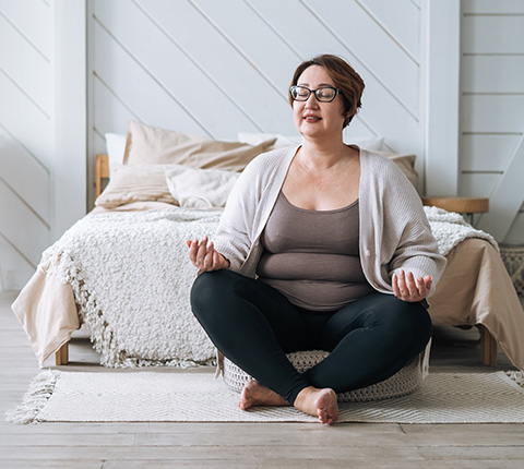 woman meditating in cozy room with bed and soft decor demonstrating mindfulness and self-care practices for mental well-being and relaxation 3 tips for mindfulness